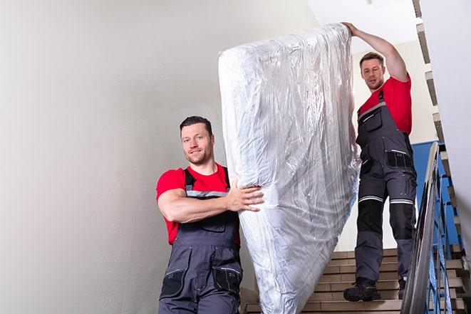 a heavy box spring being carried out of a house in Bellmawr